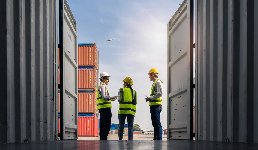 Logistics team inspecting different shipping container types at a freight terminal